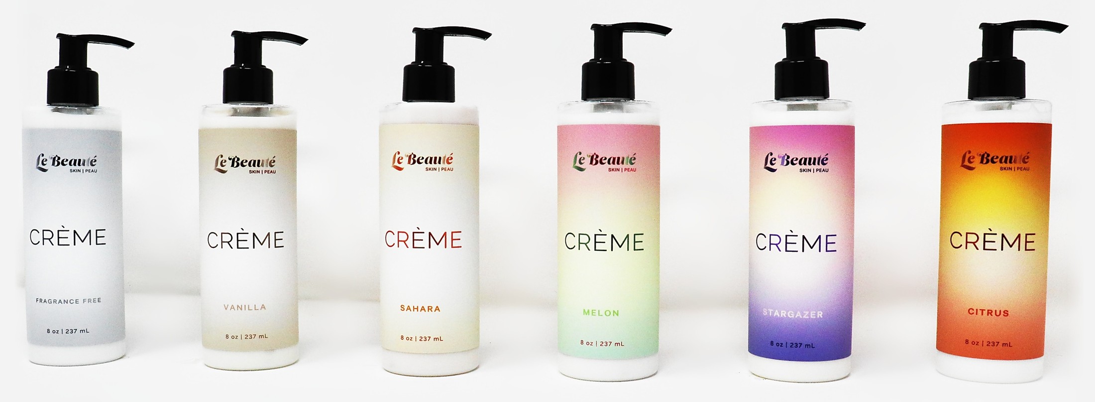 The six Le Beauté body crème bottles in a row: Fragrance Free, Vanilla, Sahara, Melon, Stargazer and Citrus.
